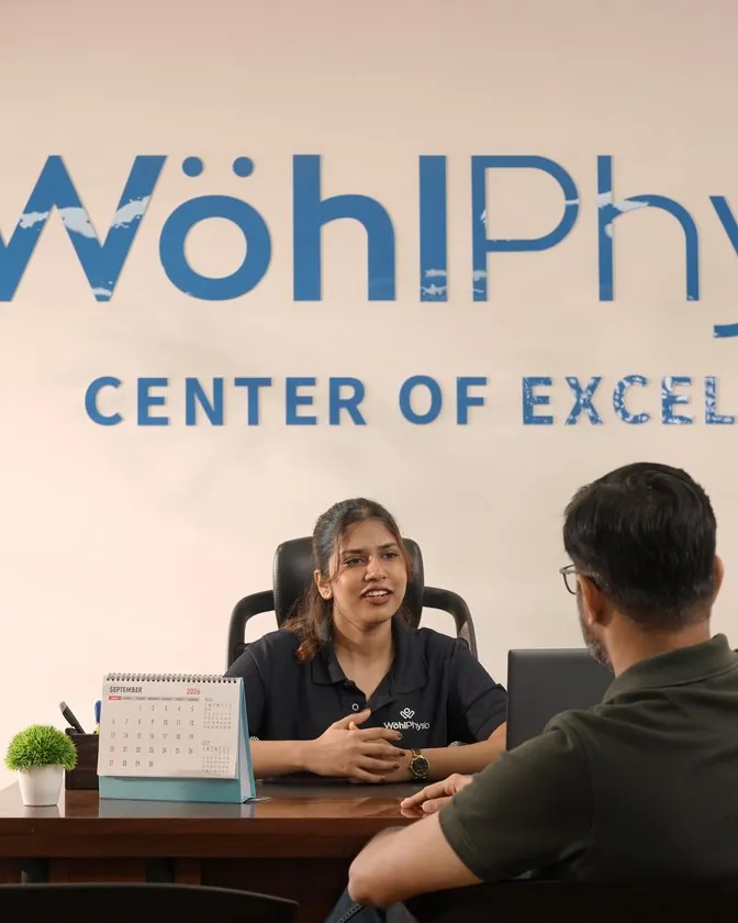 A Wohl Physio physiotherapist talking with a patient across a desk.
